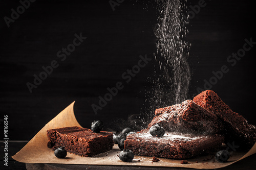 Sprinkling chocolate brownie with icing sugar and blueberry