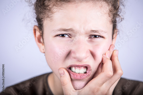 Portrait of a Young girl with toothache over white background.Child toothache with sensitive tooth ache problem touching on face the part with pain.