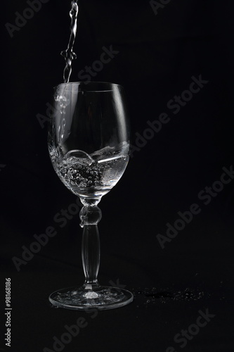 crystal cup with falling water on black background
