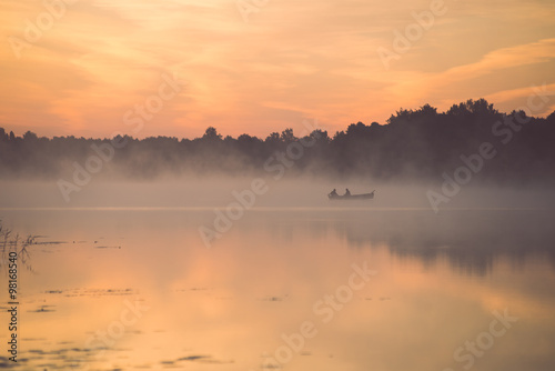 Foggy morning on the country lake with boat - vintage effect