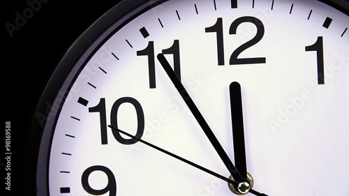 Wall clock on a black background 23:55 close-up