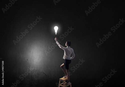 Businesswoman reaching light bulb © Sergey Nivens