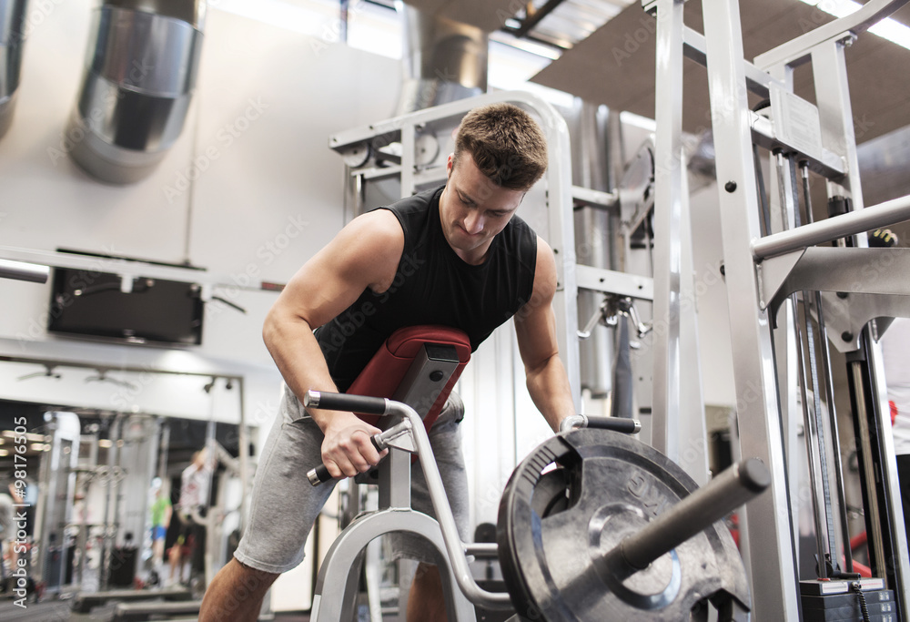 young man exercising on t-bar row machine in gym