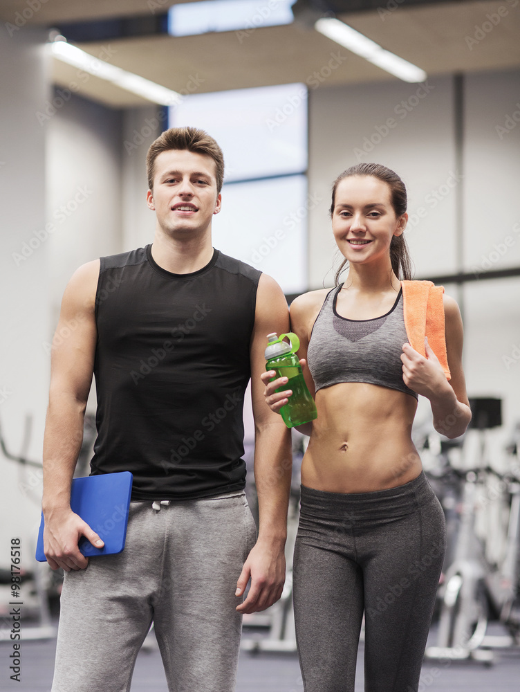 Obraz premium happy couple in gym with water and tablet pc