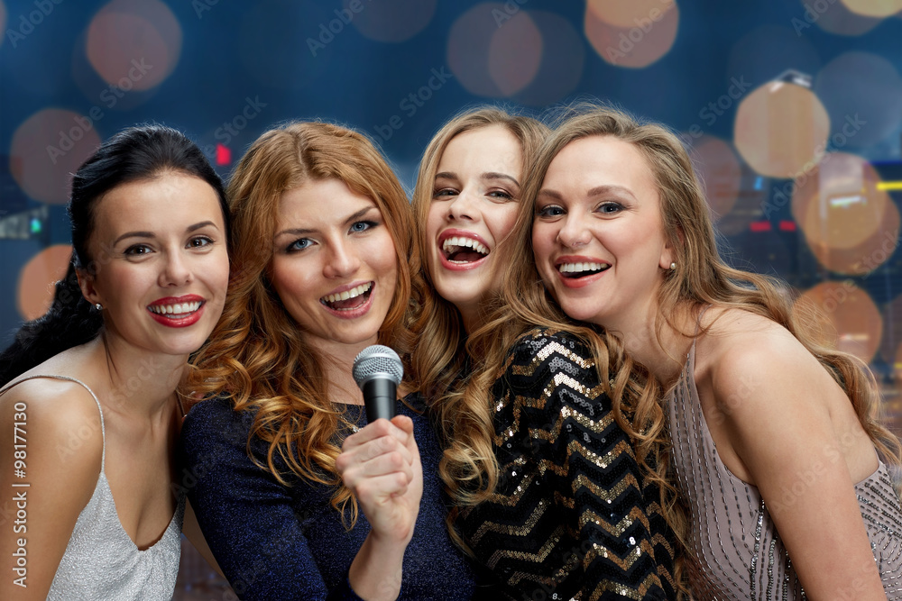 happy young women with microphone singing karaoke