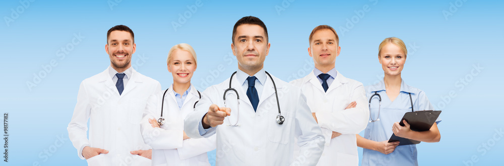 group of doctors with clipboard pointing at you group of doctors with clipboard pointing at you