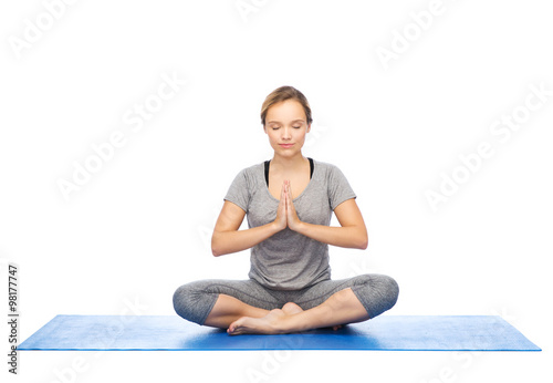 woman making yoga meditation in lotus pose on mat photo