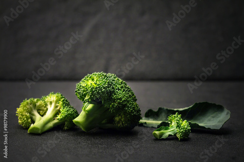 still life with fresh green broccoli on black stone plate