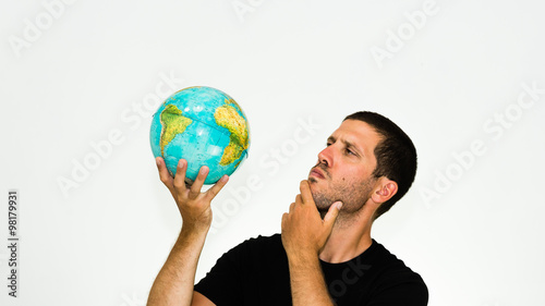 close-up of undecided caucasian man observing a world globe in his hand - conceptual image isolated on white background with copyspace