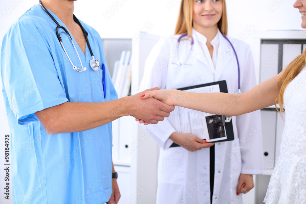 Male doctor and female patient shaking hands. Partnership, trust and medical ethics concept