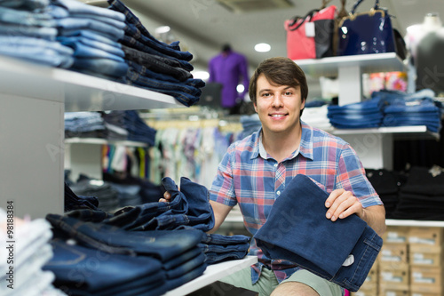 male chooses jeans at clothing store