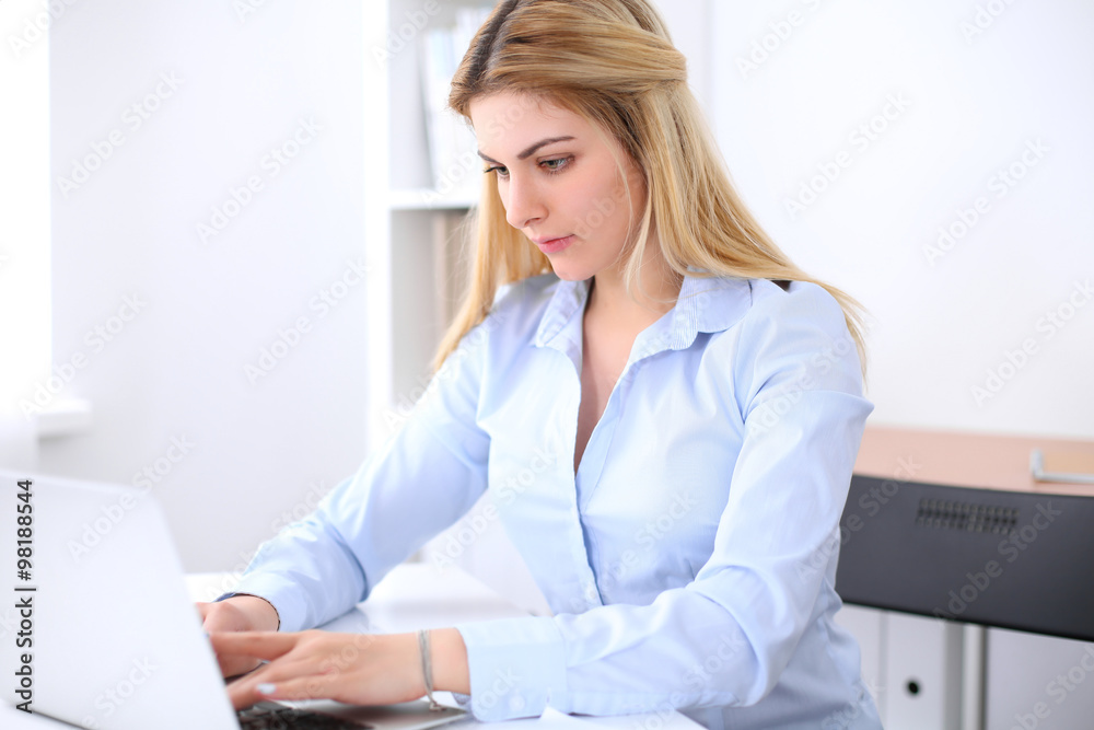 Portrait of young business woman sitting at the desk on office background Portrait of young business woman sitting at the desk on office background