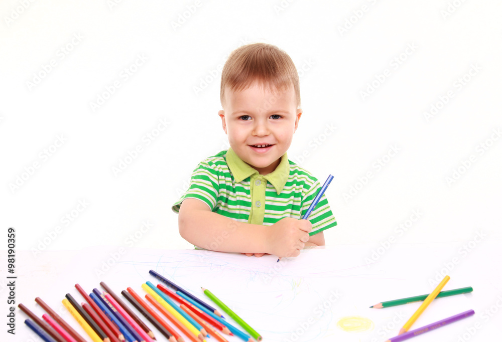 Inspired little boy at the table draw with crayons, isolated on white Inspired little boy at the table draw with crayons, isolated on white