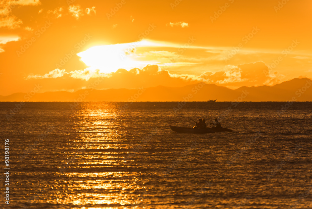 People are kayaking in the ocean while sunset
