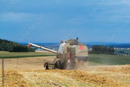 old combine on field harvesting gold wheat