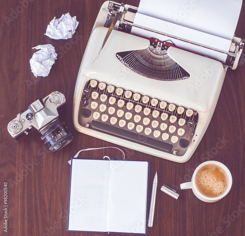 an old typewriter on old wooden table with coffee and old camera