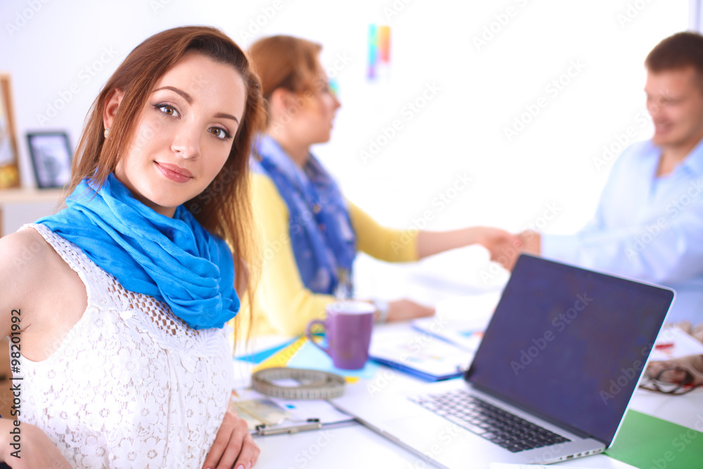 Portrait of attractive designers sitting on desk in office Portrait of attractive designers sitting on desk in office