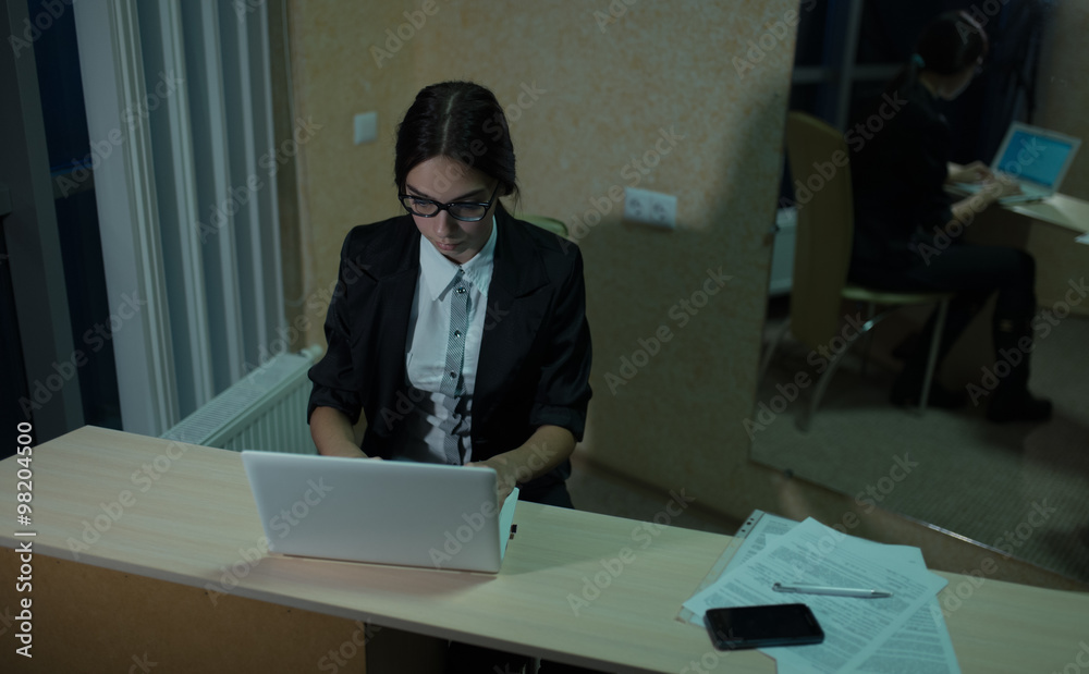 Businesswoman working at a laptop late at night in office Businesswoman working at a laptop late at night in office