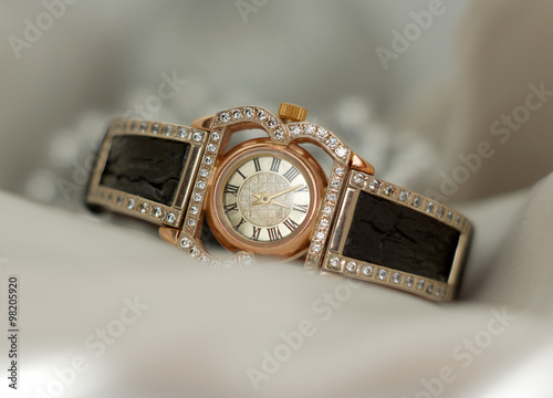 Beautiful old vintage gold watches with sparkling gem stones on a soft bokeh background