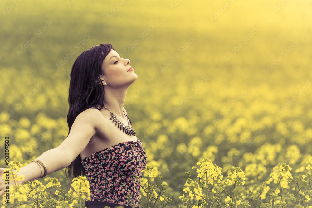 Happy positive woman in sunny summer ocean of yellow flowers. Attractive genuine young girl enjoying the warm summer sun in a wide green and yellow meadow. Copyspace in the right. Happy positive woman in sunny summer ocean of yellow flowers. Attractive genuine young girl enjoying the warm summer sun in a wide green and yellow meadow. Copyspace in the right.