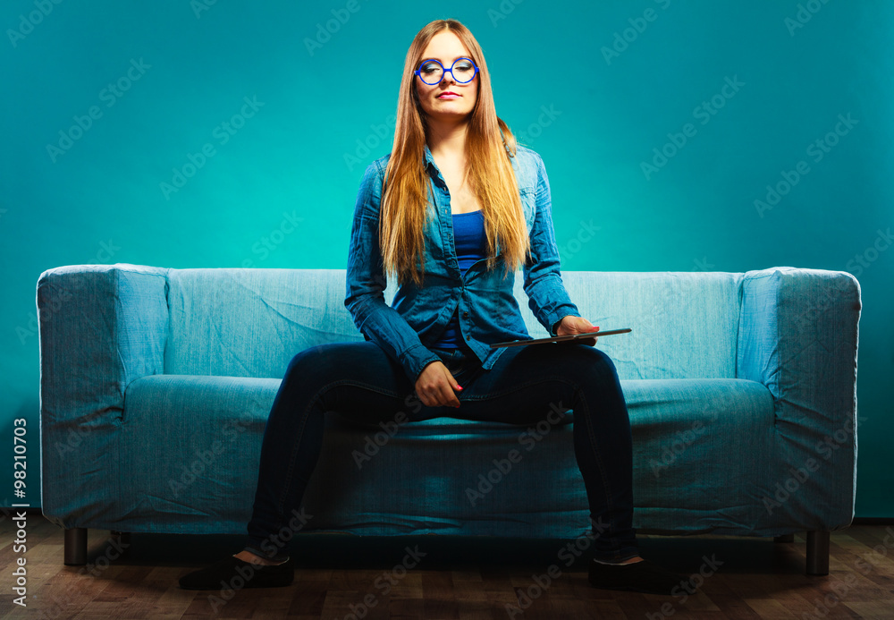 Fashionable girl wearing denim sitting on couch.