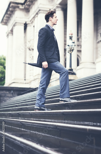 Young business man on way to work climbing steps