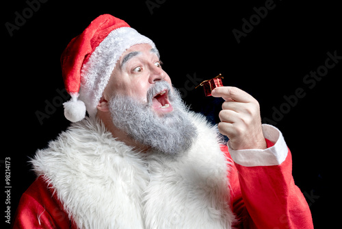 Santa Claus surprised looking at a very small gift