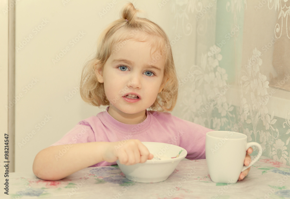 Little girl eats porridge from sitting at the table. Little girl eats porridge from sitting at the table.