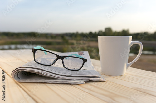 Close up glasses with newspaper and Coffee on the table in the morning selective focus