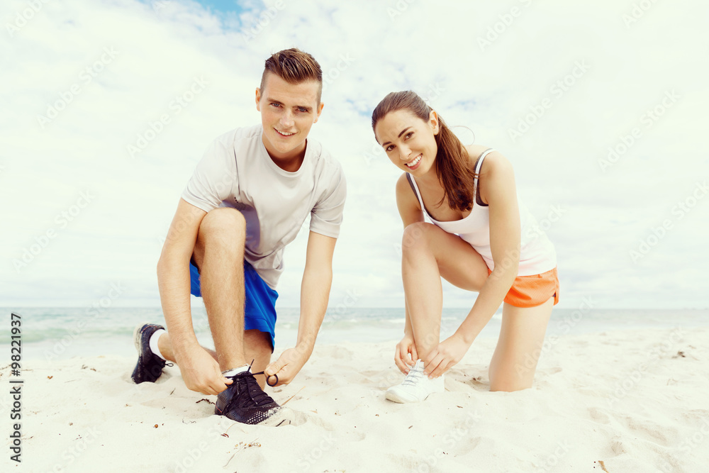 Fototapeta premium Runners. Young couple exercising and stertching on beach