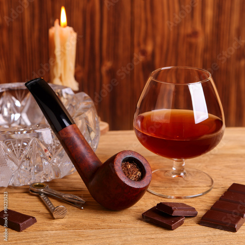 Fototapeta Naklejka Na Ścianę i Meble -  A glass of cognac, chocolate and smoking pipe