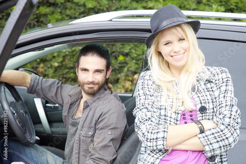 Happy hipster couple in front of car smiling looking camera © fmarsicano