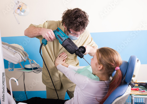 Crazy dentist treats teeth of the unfortunate patient. The patient is terrified. The dentist drills drill teeth photo