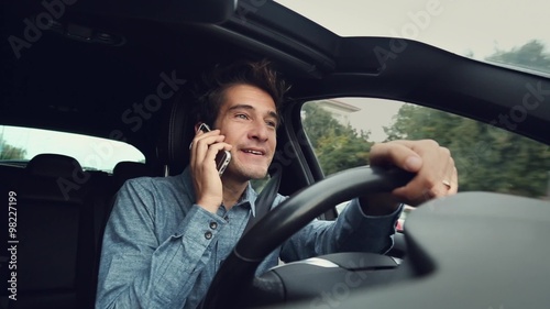 Happy man talking on the phone while driving car