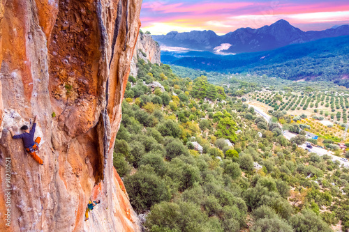 High colorful rock and two climbers ascending photo