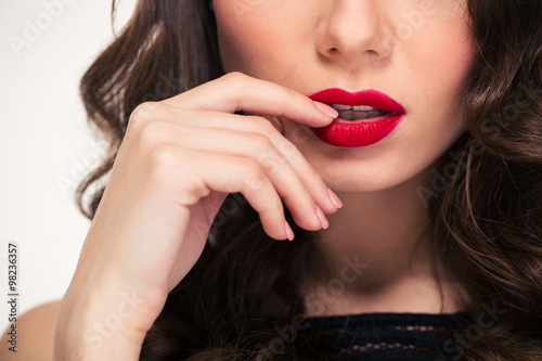 Tempting red lips of curly woman touched by her hand