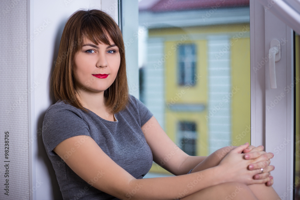portrait of young woman sitting on window sill portrait of young woman sitting on window sill