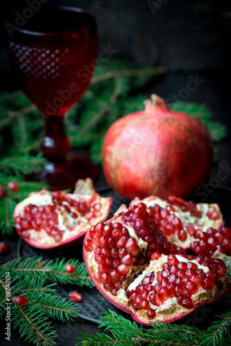 Pomegranate with festive decorations over wooden background
