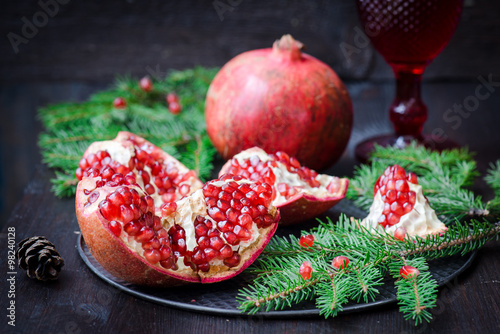Pomegranate with festive decorations over wooden background
