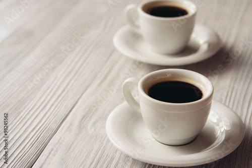 Two cups of coffee on a white wooden table