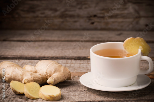 Ginger tea in a white cup on wooden background