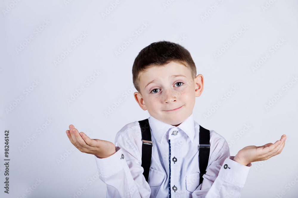 Confused little boy gesture over grey background.