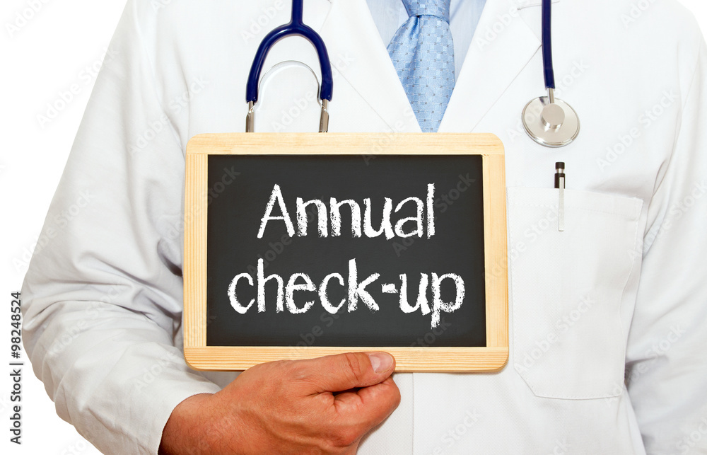 Annual check-up - doctor holding chalkboard with text on white background Annual check-up - doctor holding chalkboard with text on white background