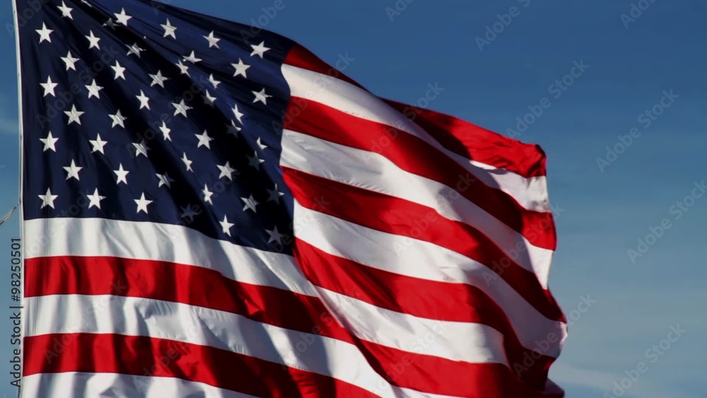 Loop features the flag of the United States of America flying in the wind against a blue sky with high wispy clouds.