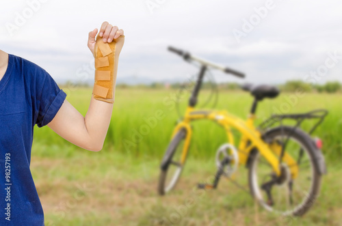 Hand with a wrist brace, orthopedic equipment with yellow bicycl photo