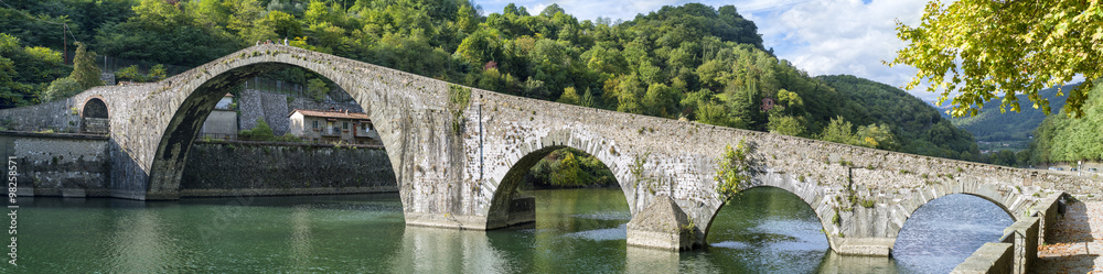 panoramic view to old bridge  with arch's through the green river in Italy