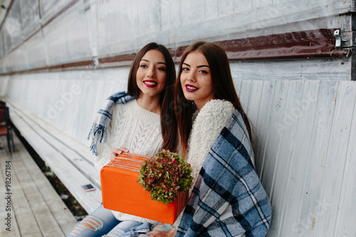 Two beautiful girls holding gift