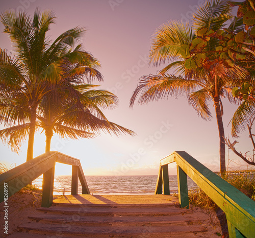 Sunrise summer scene in Miami Beach Florida with a path going to the ocean and beautiful palm trees, Instagram desaturated filter for retro looks photo