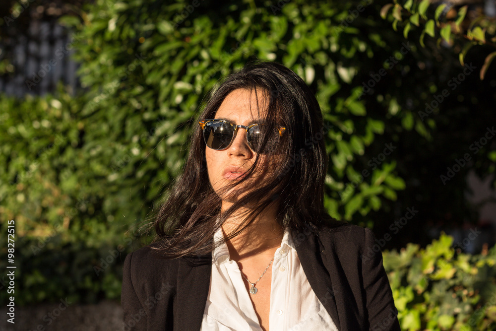 Businesswoman. Pretty Latina business woman posing in a photo session in the sun. She wears sunglasses and elegant black suit with white shirt. Businesswoman. Pretty Latina business woman posing in a photo session in the sun. She wears sunglasses and elegant black suit with white shirt.
