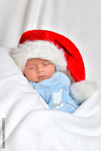 Kleines Baby ist am schlafen und trägt eine Weihnachtsmütze